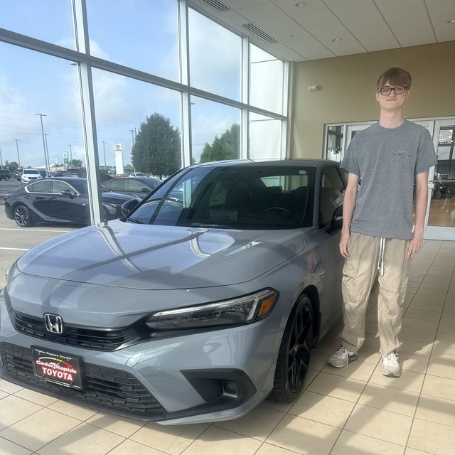 Nathan standing next to his gray Honda Civic at the dealership